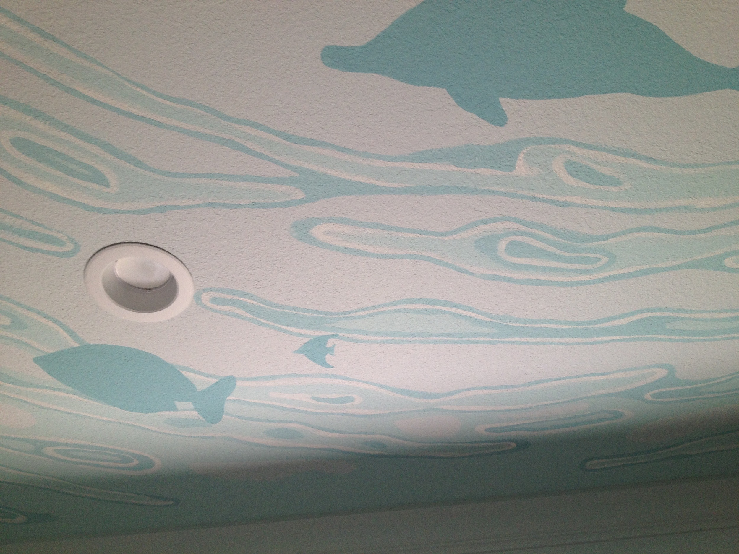 Fish and dolphins swim around the ceiling in cool shades of blue.