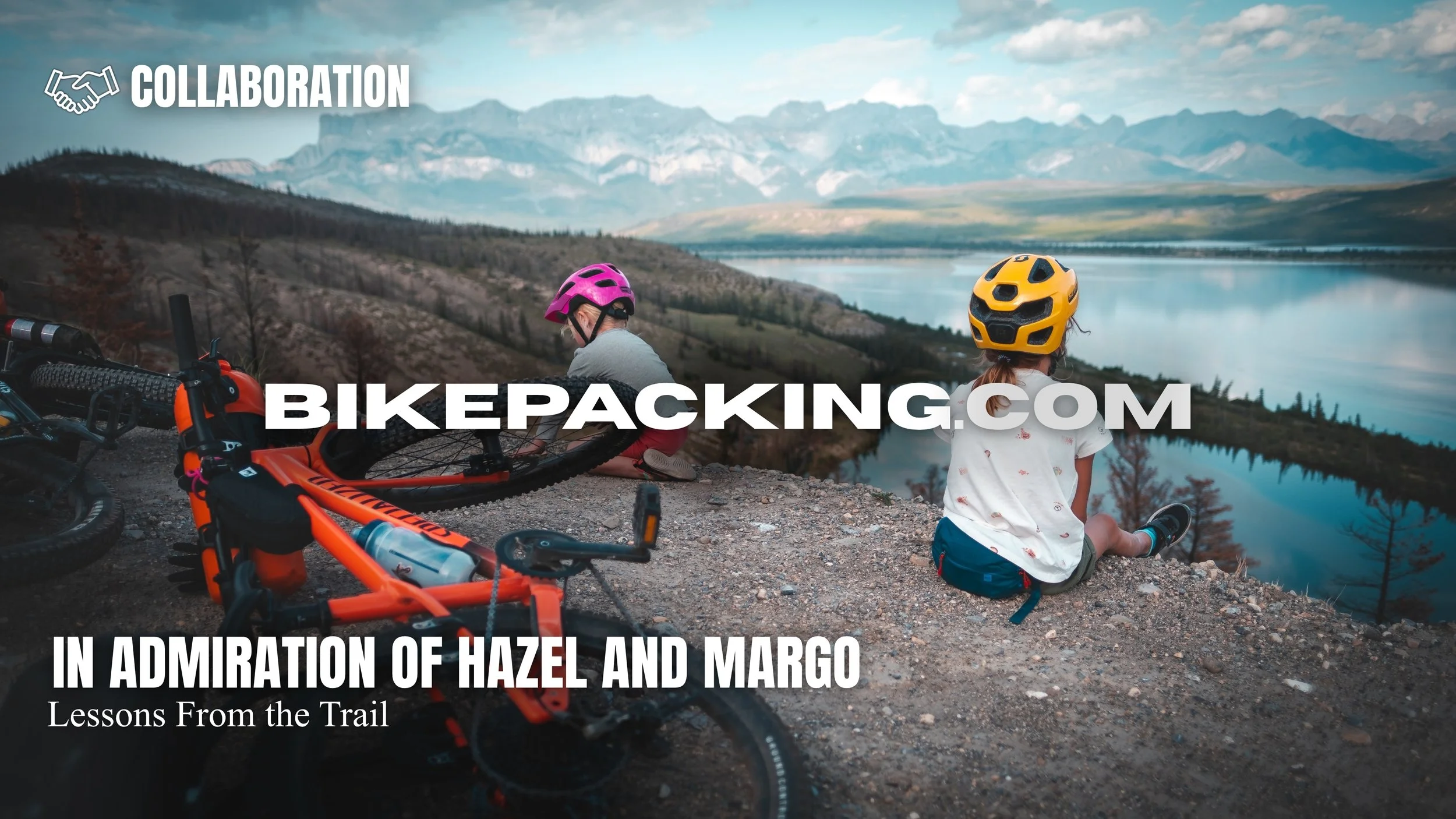 Two children with helmets sitting on the ground near mountain bikes, overlooking a scenic lake and mountain range in the distance.