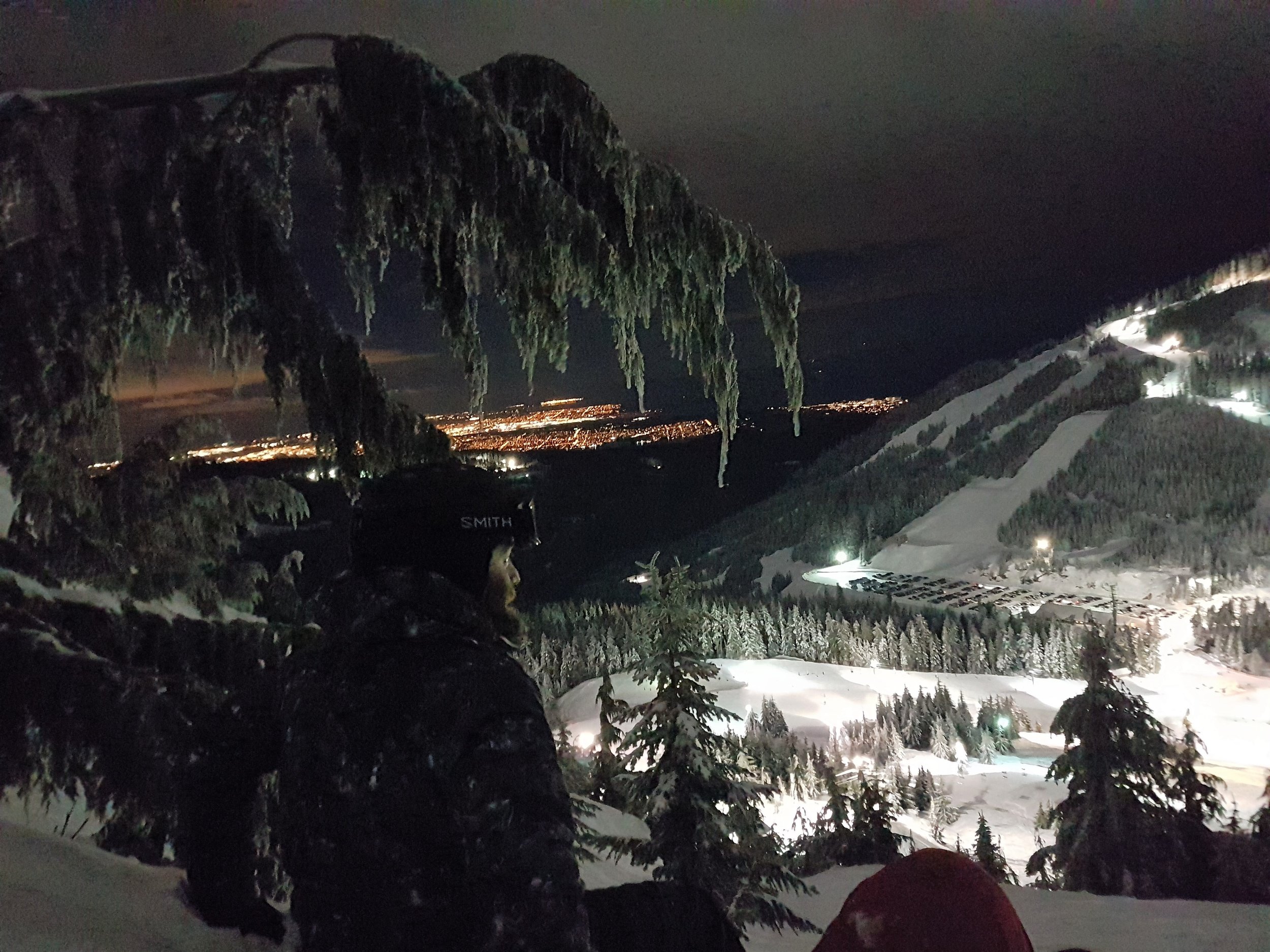 Snowboarder overlooking the local slopes in Vancouver during night time