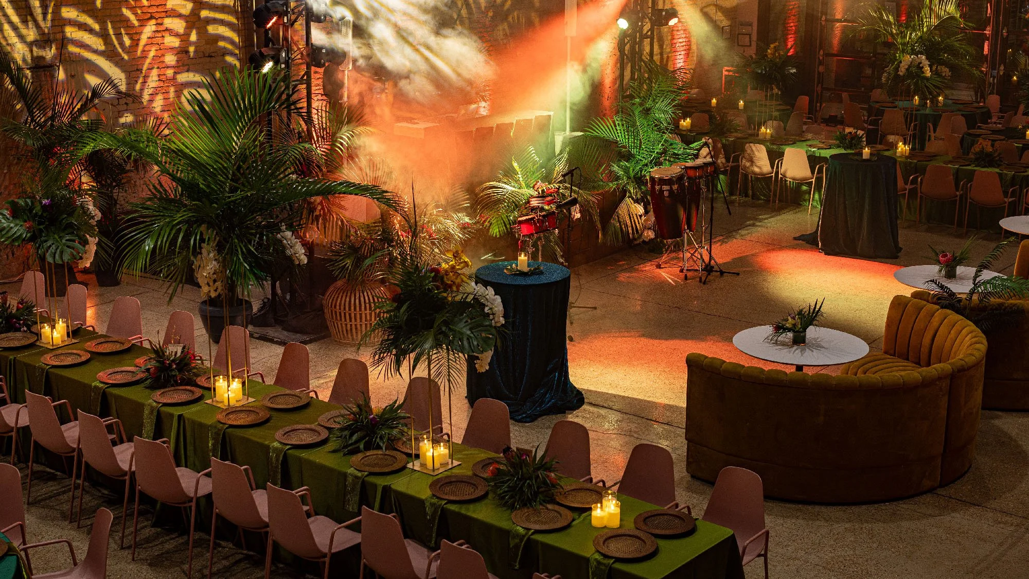 Industrial venue with tropical tablescapes, warm lights, and lush florals