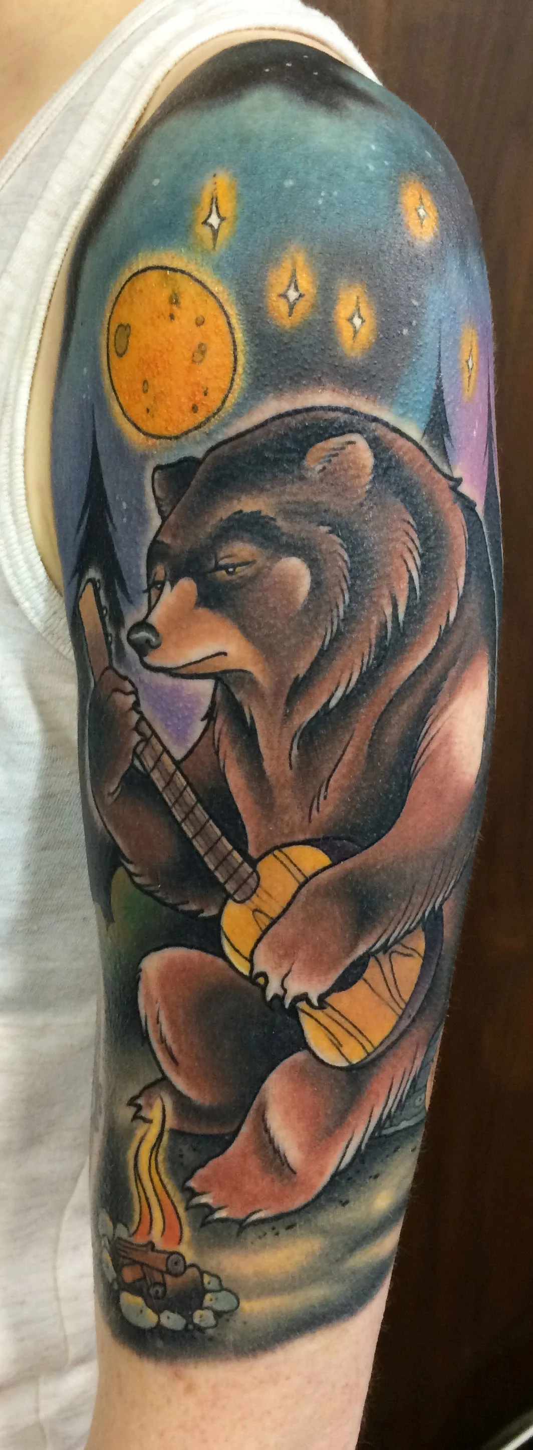 bear playing guitar by a campfire.