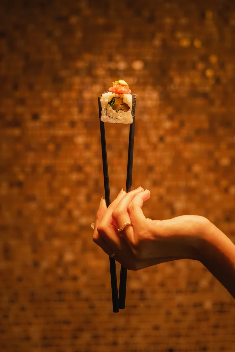 Chef presenting gourmet sushi with chopsticks, hotel food photography by David McConaghy