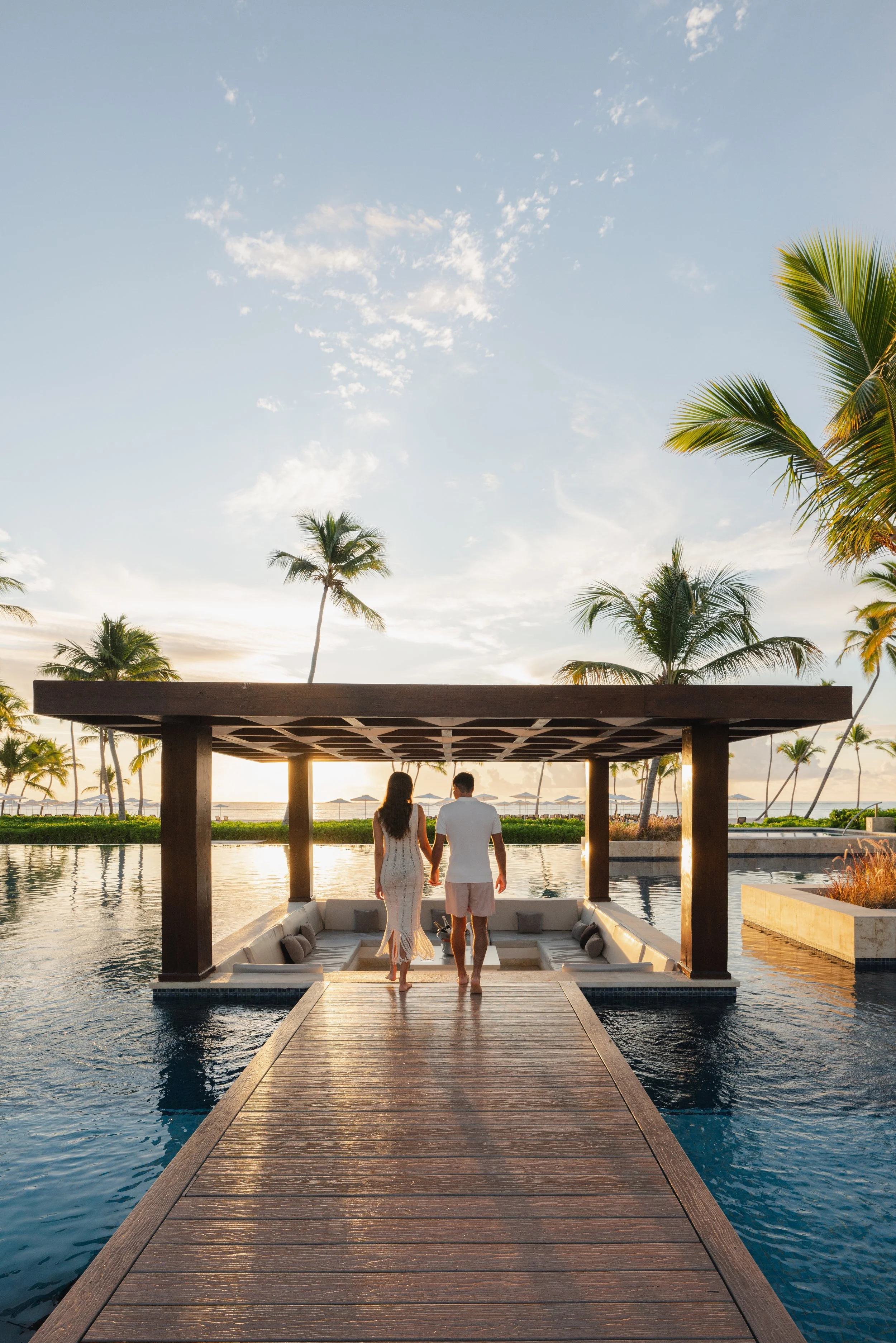 Couple walking along infinity pool jetty at sunset, luxury resort photography by David McConaghy
