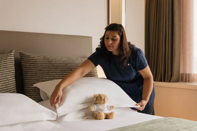 Hotel housekeeper preparing bed with swan towel sculpture, staff photography by David McConaghy