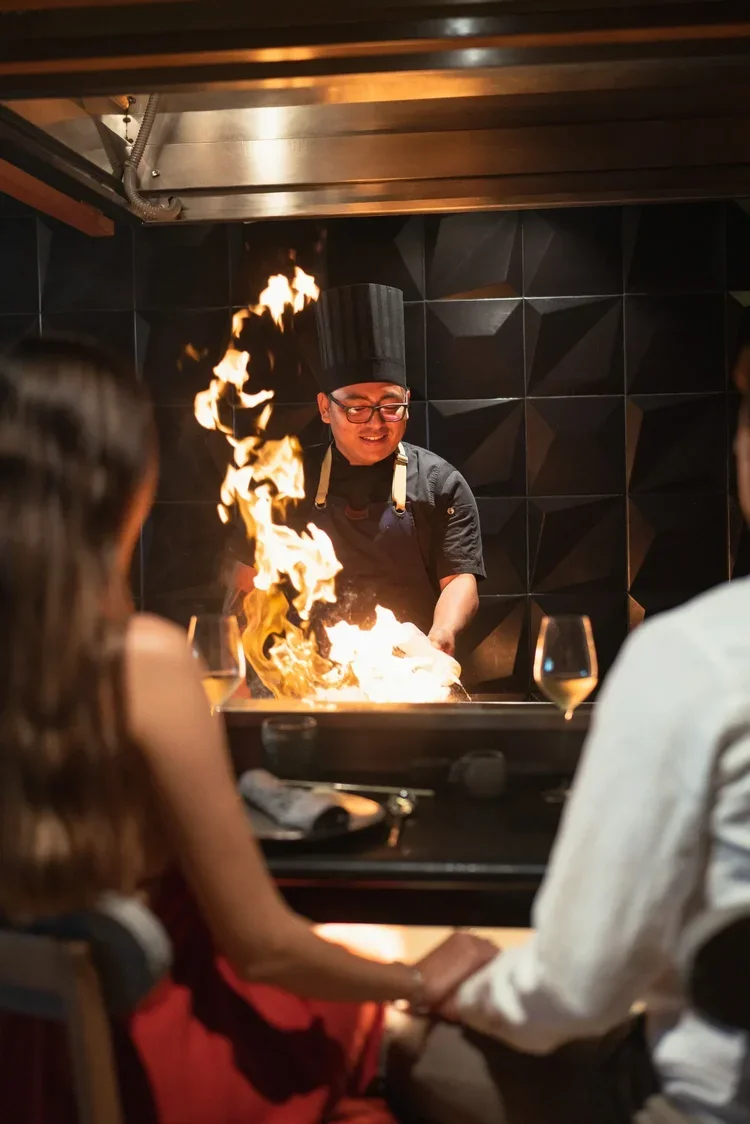 Hotel chef performing flambé tableside for guests, staff portrait photography by David McConaghy