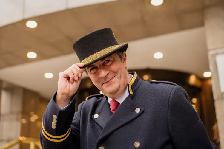 Hotel doorman in uniform tipping hat, staff portrait photography by David McConaghy