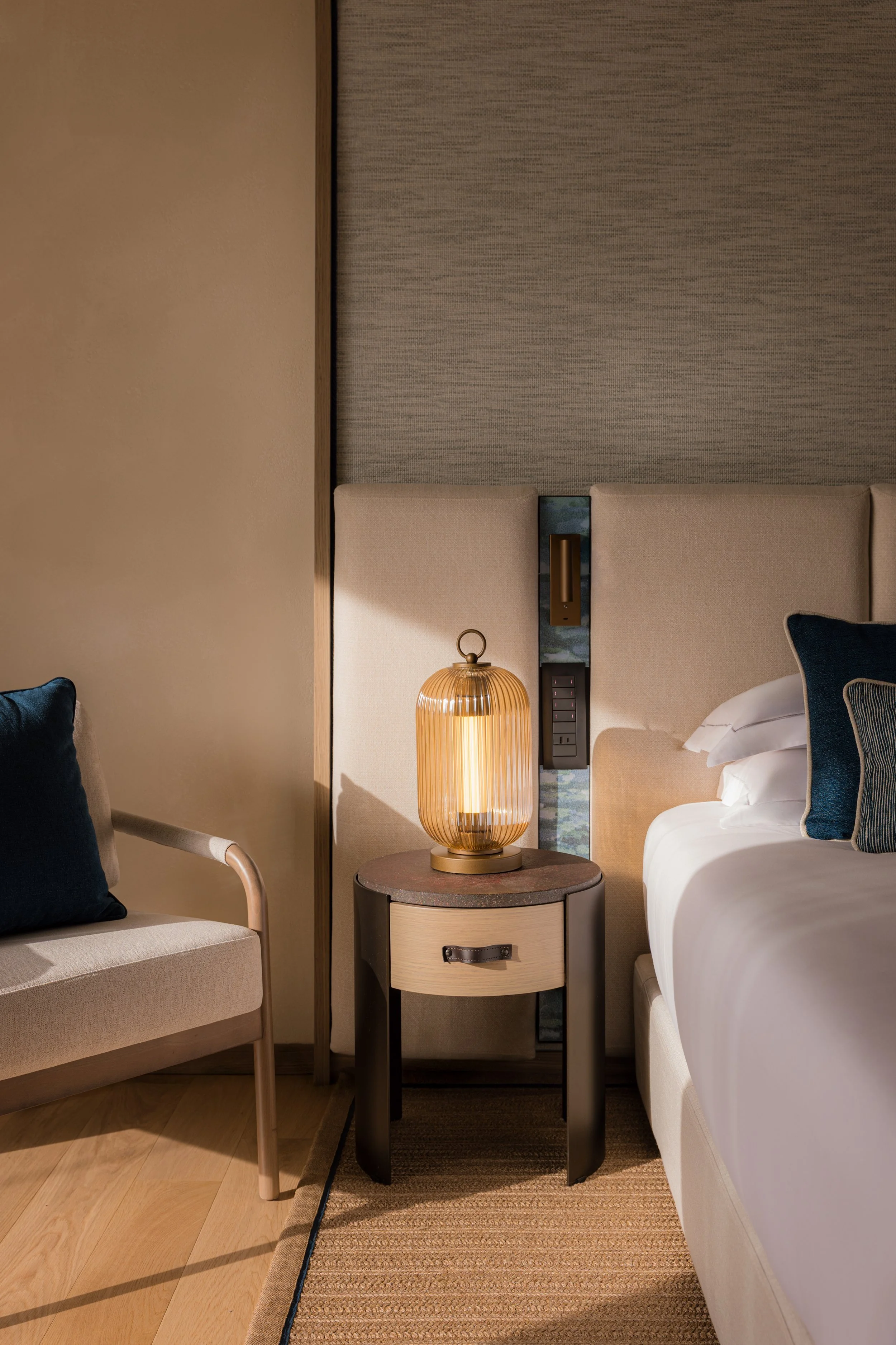 Luxury hotel bedroom detail with bedside lamp and blue cushions, interior photography by David McConaghy