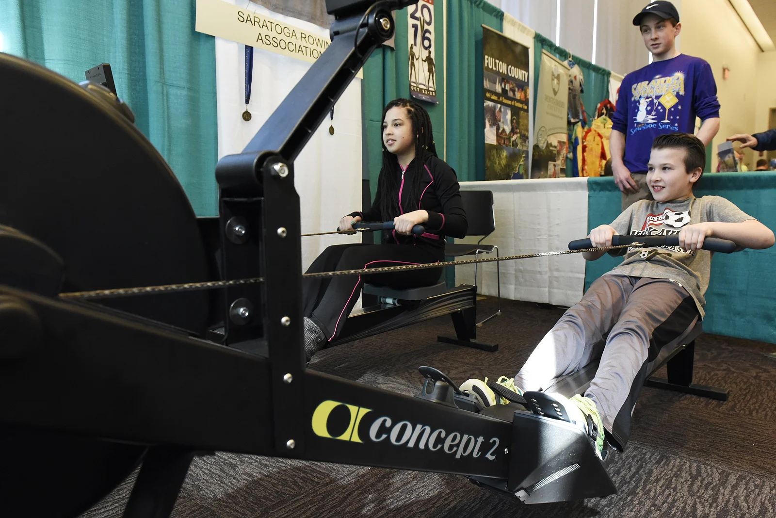 ERICA MILLER / GAZETTE PHOTOGRAPHER Makayla LaGuerre, 13-years-old of Chestertown, and cousin Carter Coulter, 10-years-old of Queensbury, compete 500m at the Saratoga Rowing Association booth during the Adirondack Sports Summer Expo at the Saratoga Springs City Center on Saturday afternoon, March 18, 2017.