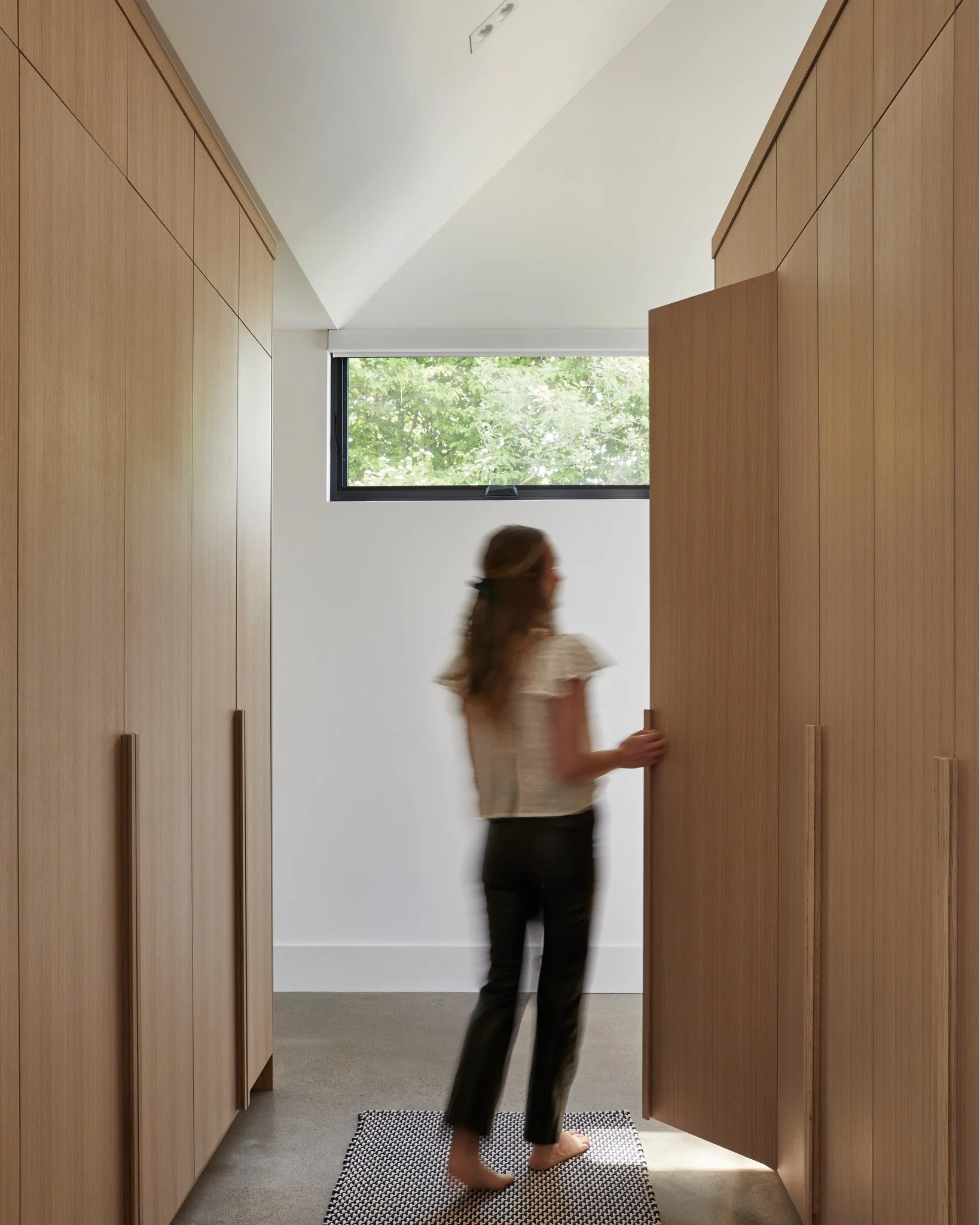 A walkthrough dressing area can help keep a primary bedroom open and airy.  Extra width is needed to accommodate a walkaround bed with side tables, so it's not always the preferred layout.  In this case the millwork was also kept lower behind the hea