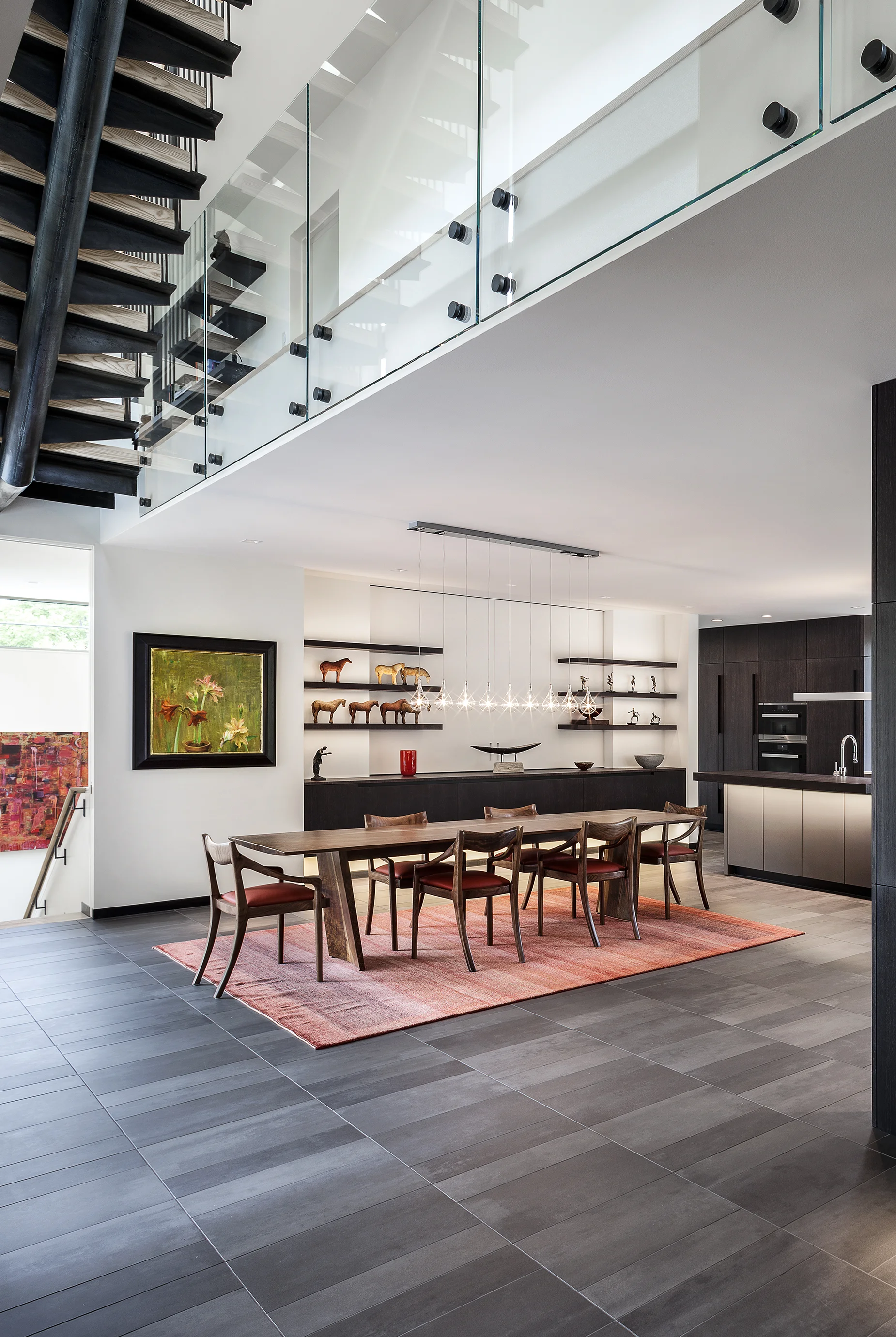 Bonnie Brae Residence The Dining Room area features a wall of floating cabinetry with five foot wide drawers allowing for plenty of cutlery, platters and centerpieces to be used in this area. The 80mm thick cantilevered shelving floats and allows for integrated LED lighting to illuminate the art and decorative elements on display. With the center matt glass section featuring free floating sliding glass doors, that open to reveal a TV for easy viewing.