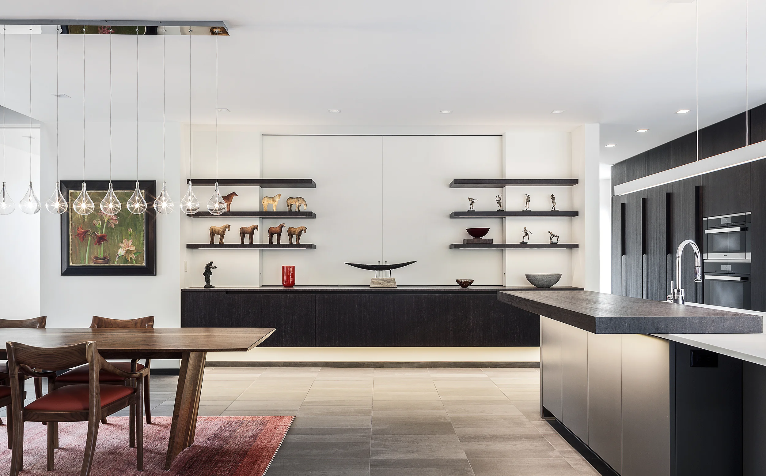 Bonnie Brae Residence The Dining Room area features a wall of floating cabinetry with five foot wide drawers allowing for plenty of cutlery, platters and centerpieces to be used in this area. The 80mm thick cantilevered shelving floats and allows for integrated LED lighting to illuminate the art and decorative elements on display. With the center matt glass section featuring free floating sliding glass doors, that open to reveal a TV for easy viewing.