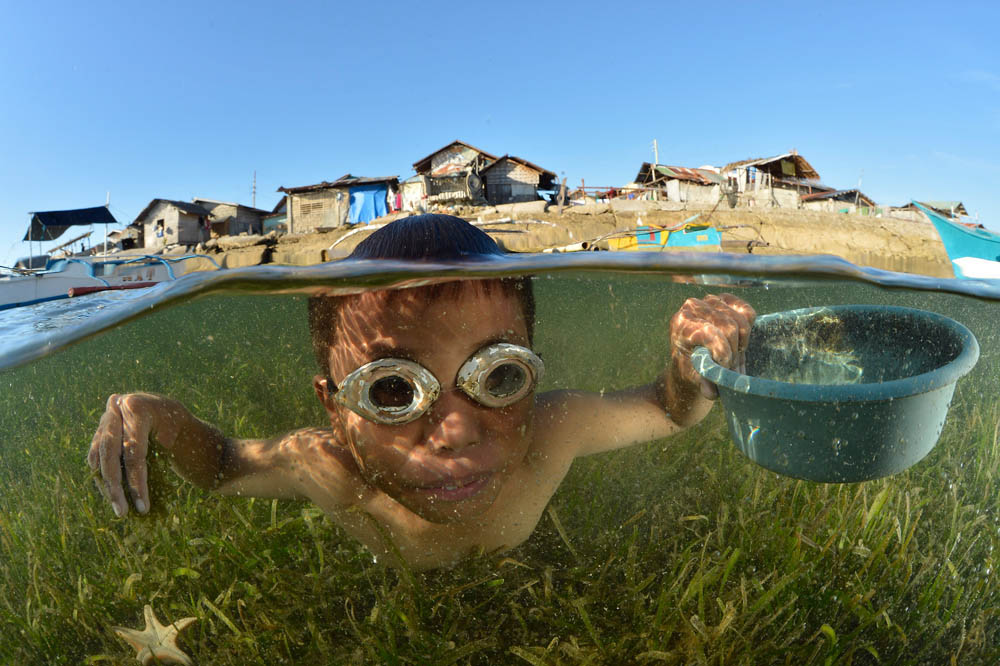 A young boy gathers crabs, shellfish, and nudibranch eggs just off the shore of his island village. Luciano Candisani/iLCP