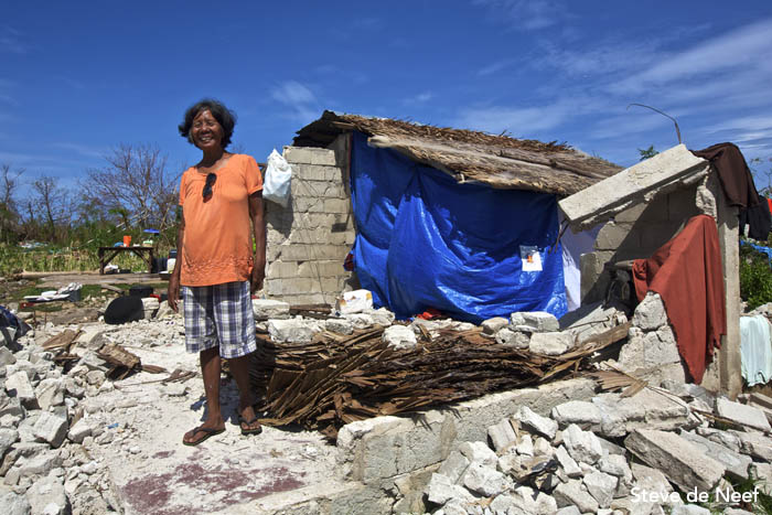 A woman posing in from of her house that was destroyed by Tyhpoon Yolanda.