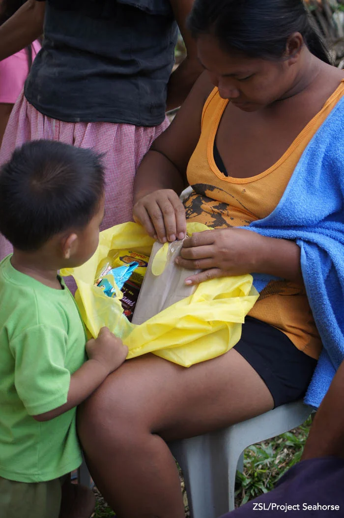 A woman opens one of the packs for her young child. Photo: Chai Apale/Project Seahorse