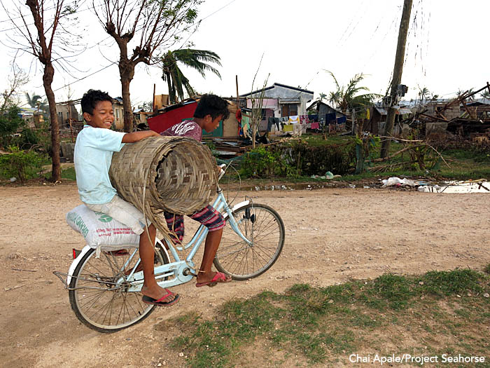 A pair of boys transport rebuilding materials by bike through their village. Photo: Chai Apale/Project Seahorse