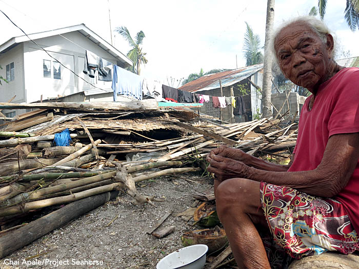 A woman sits in front of the ruins of a house in Bantayan Town. Photo: Chai Apale/Project Seahorse