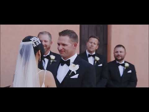 Bride and groom exchanging vows during wedding ceremony with groomsmen in background.