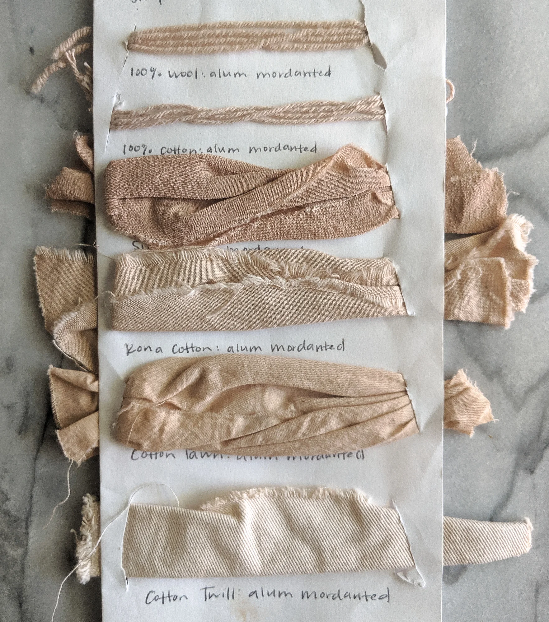 My sample card (circa 2015, wowieee!) cataloging how different materials absorb avocado skin and pit dye. Top to bottom: wool yarn, cotton yarn, cotton silk, Kona© cotton, cotton lawn, and heavy cotton twill.