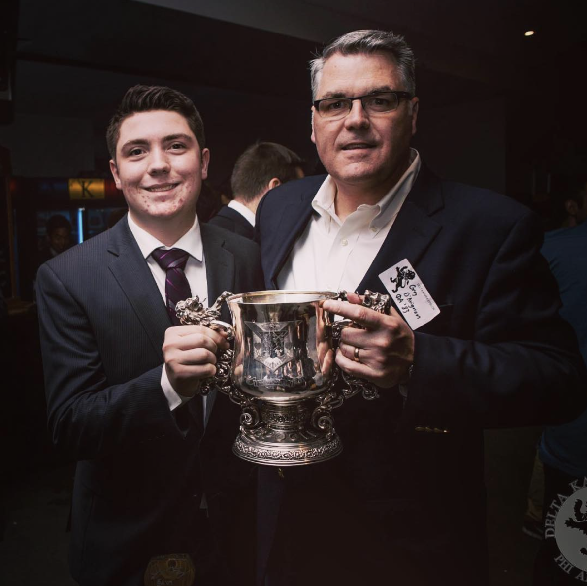 Father and son Matt D'Avignon (PA '14) and Gerry D'Avignon (PA '83) show off The Lion Trophy, awarded annually to the best ∆KE Chapter.