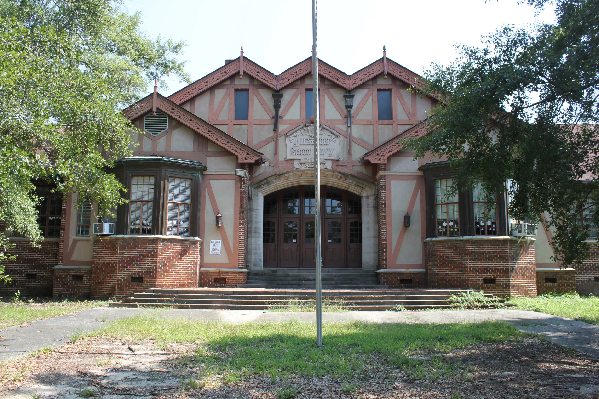 Alexander IV Elementary School was established in 1932 as the fourth free school supported by the Elam Alexander Trust. Mr. Elam Alexander, a notable architect, believed that free, quality education was paramount for the success of individuals, which in turn would lead to the success of Macon as a community. During his lifetime, Mr. Alexander gave generously to many educational institutions, and in his will, he set up the Alexander Free School Board, later known as the Elam Alexander Trust. This organization continues to promote education in Macon-Bibb County. This particular elementary school was built in the Ingleside neighborhood to relieve overcrowding at the Bellevue and Clisby Schools. The Ridge Avenue location was more convenient for many of its new students, who lived in the recently established Ingleside neighborhood. The community waited in great anticipation for its new school, which the Macon Telegraph described as a “gabled, bronze-hued, English type” building. Such was the anticipation that the newspaper even wrote a description of the interior: “the mellow cream and brown interior of the school with its bronze trimmings and rose-tiled floors.” The excitement continued after Alexander IV’s opening. Ms. Nell Collins, who both taught the seventh grade and served as the first principal, asked the Parent Teacher Association to hold a special tea, which formally unveiled the school in November 1932. Just a month earlier, a plaque was dedicated to Elam Alexander at the front entrance of the school. That plaque is still in place today. Alexander IV’s prominent role in the community continued in many ways through the twentieth century. For instance, the school fielded a dominant football team for Macon’s annual Pony Bowl, a football game played around Thanksgiving, from 1949 to 1960. The school’s integral role in the community came to a close in June 2011, when Alexander IV closed its doors to students. Today, the building’s steeply pitched gables, exposed beams, and intricate ornamentation stand empty to students. The Bibb County Board of Education declared the building surplus in 2013 and is seeking a new use for the significant building, which is a contributing building in the proposed Ingleside National Register District. Historic Macon Foundation looks forward to working with the neighbors and the Board of Education to find a new use for the iconic school building. Across the country school buildings have been adapted to multiple uses, and we are confident Alexander IV will once again be an anchor and asset for the community. UPDATE: The Bibb County Board of Education approved the sale of Alex IV to the Macon-Bibb Country Land Bank Authority. The Land Bank Authority will hold the building as Historic Macon works with a committee to send out a request for proposal to developers. Dover Development has been selected to renovated Alex IV into a senior living facility. Read more.