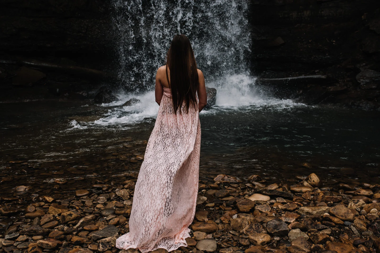 mom stands near waterfall at cucumber falls in ohiopyle for maternity session