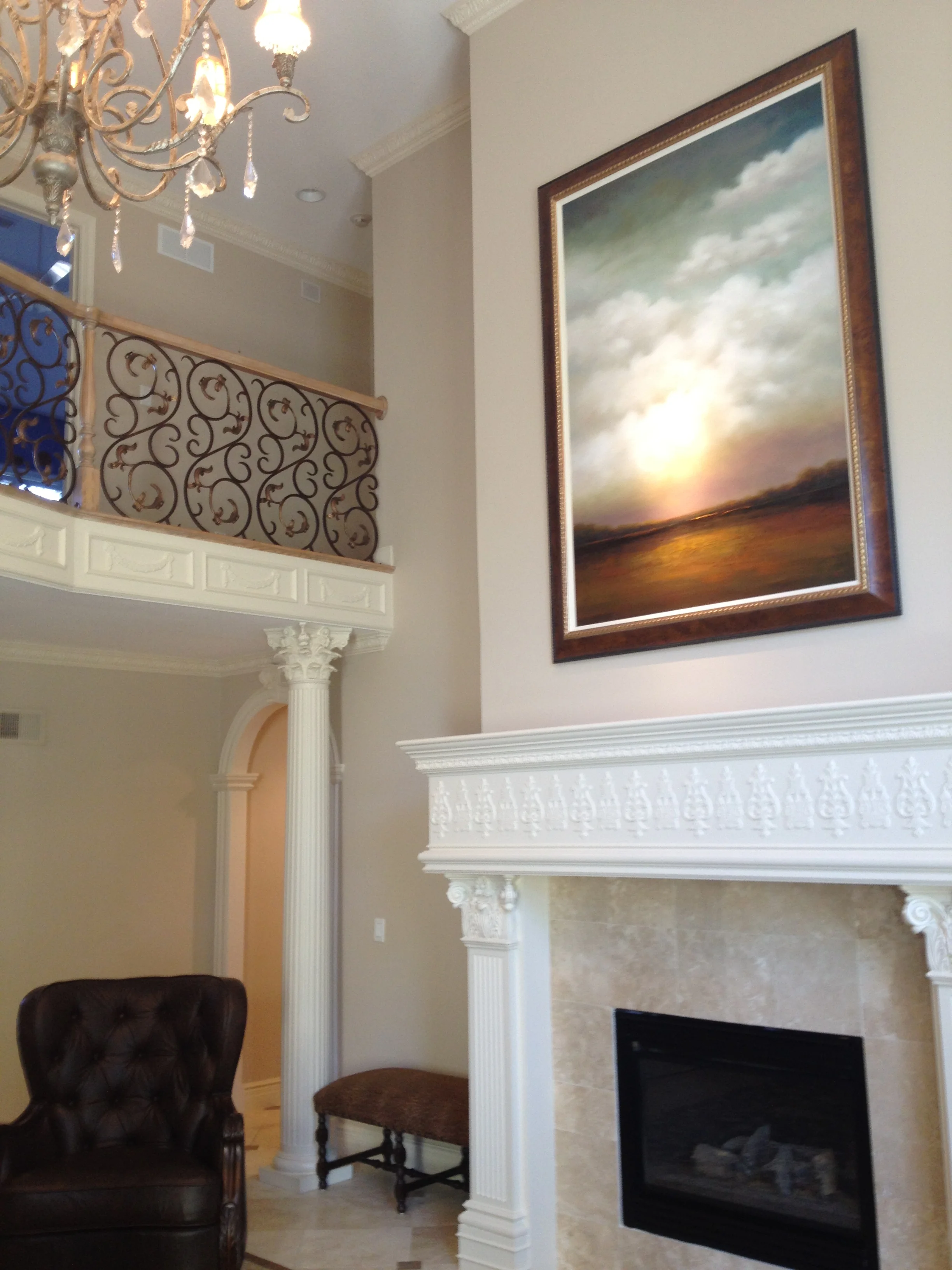 The large scale and soaring skies of this painting connects the first and second floor of this home.