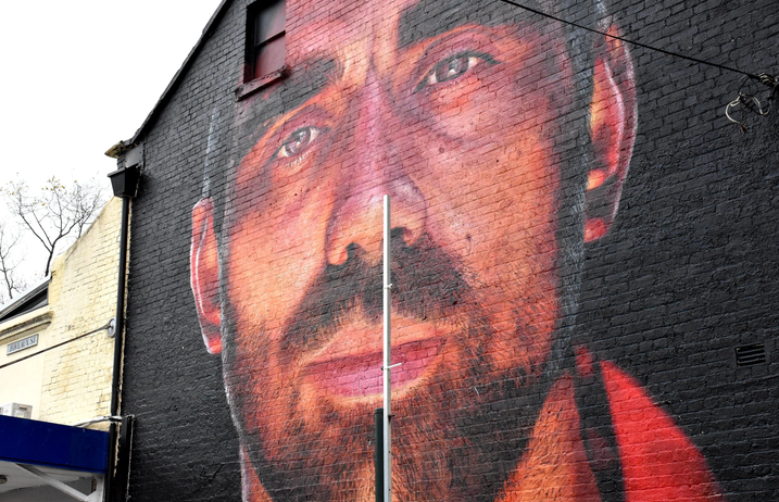 A large, detailed mural of a man’s face is painted on a brick building wall in Surry Hill, showcasing the vibrant street art scene