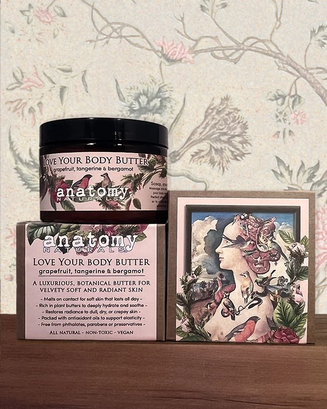 The Anatomy Naturals Love Your Body Butter jar resting atop its elegant, custom-designed product box, showcasing the luxury packaging and brand aesthetic for this targeted treatment for crepey skin.
