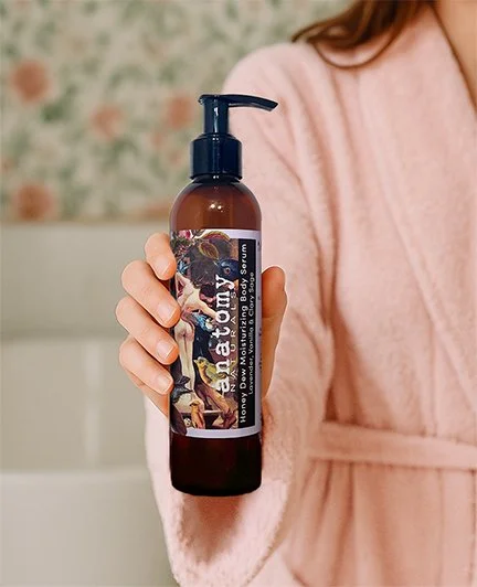 woman in a bathrobe holding honey dew moisturizing body serum
