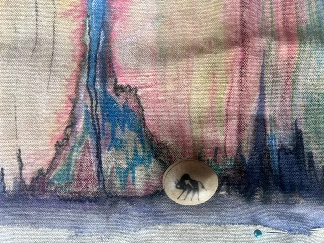 Abstract watercolor painting with colorful vertical brushstrokes, a button featuring a black animal silhouette, and a small blue-headed pin