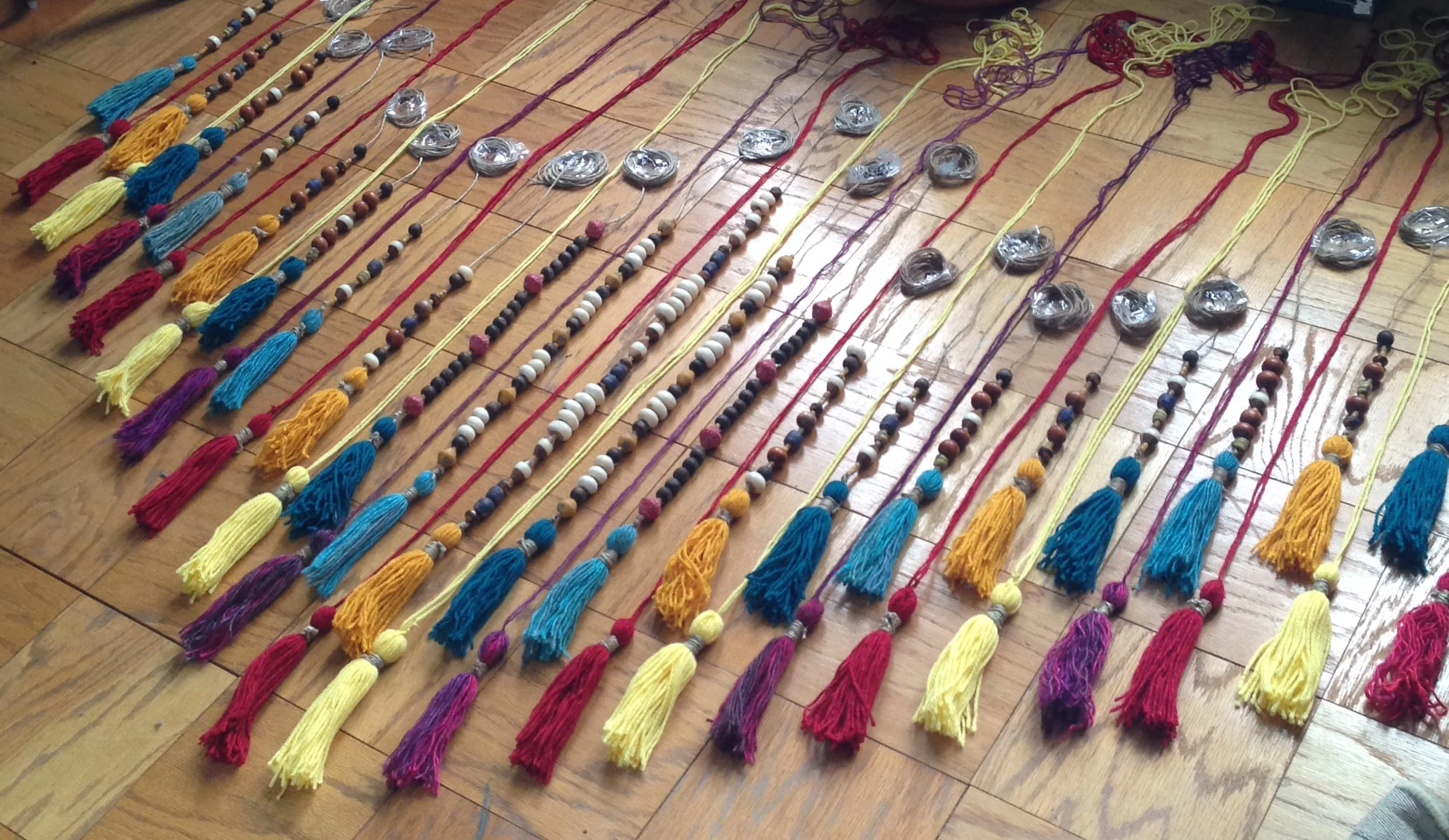 Finally, I laid it all out on my living room floor exactly how I was going to hang it up. The top row has beads on twine because the yarn alone is not strong enough to hold the weight of the beads. The bottom row is only yarn and tassels, no beads.