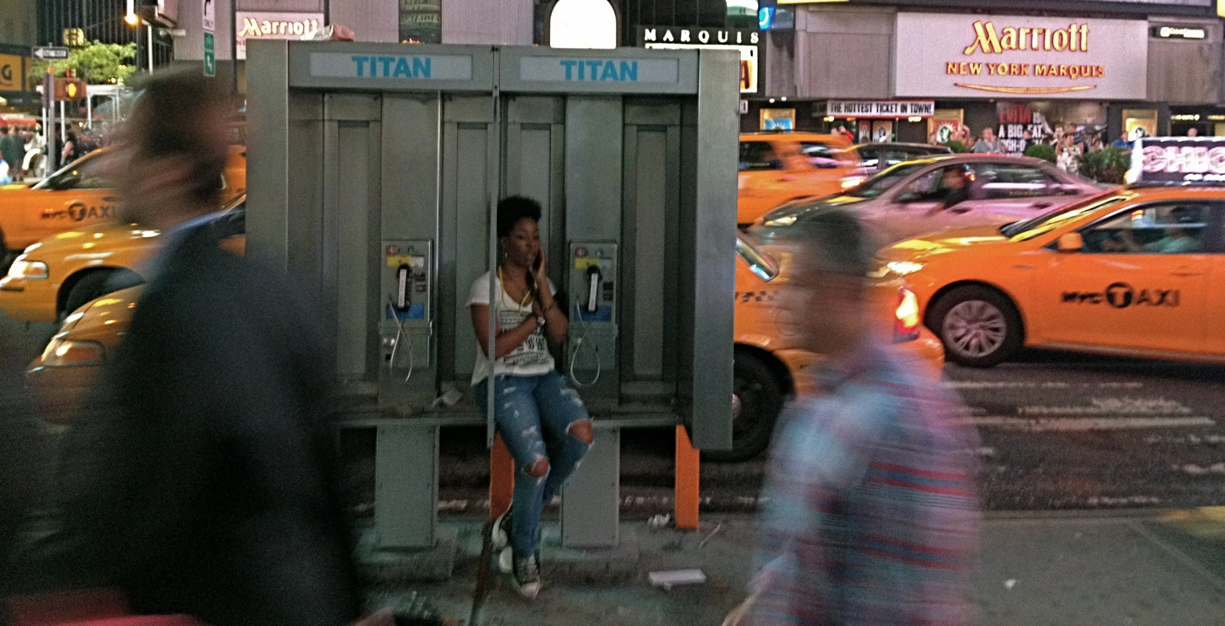  A woman cozies in a phone booth using her cell to talk to “My sister. She’s getting married next week. We are deciding on color schemes. Why you listening to my conversation though?” 