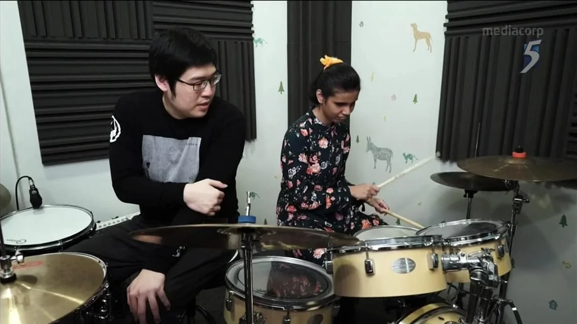 Chun Leng teaching Nurul how to play the drums.
