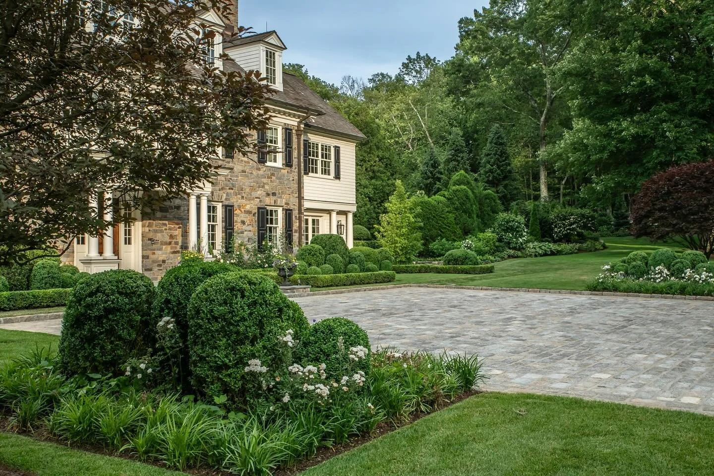 The first impression starts at the driveway. ✨ Neatly shaped globes, layered plantings, and a wide stone court create a welcoming arrival. Mixed trees frame the home with beauty and privacy, giving it a look that is classic and lasting.

@jonathanhop