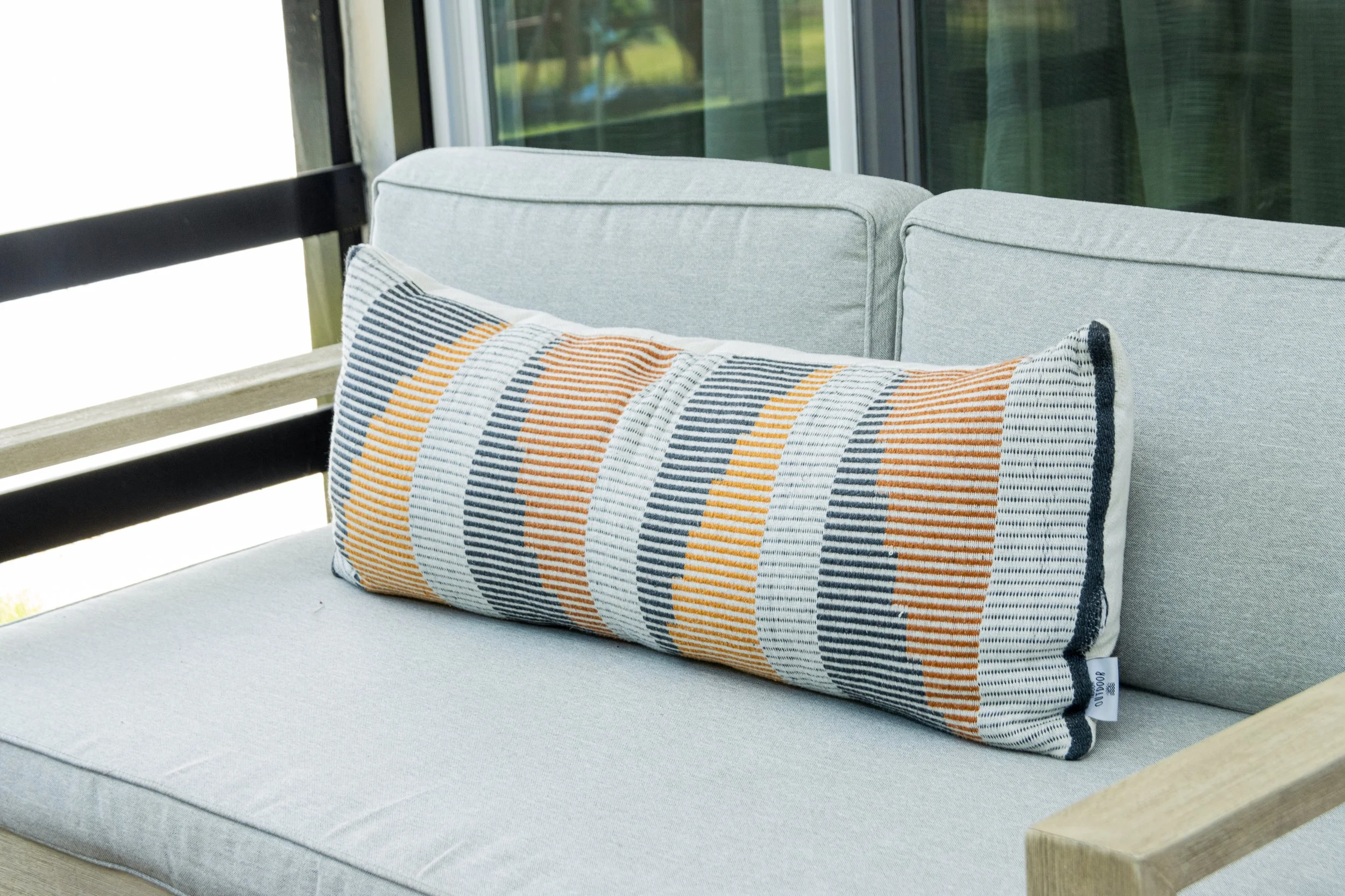 outdoor-kidney-pillow-in-calm-sun-room-with-textures-and-soft-color-palette