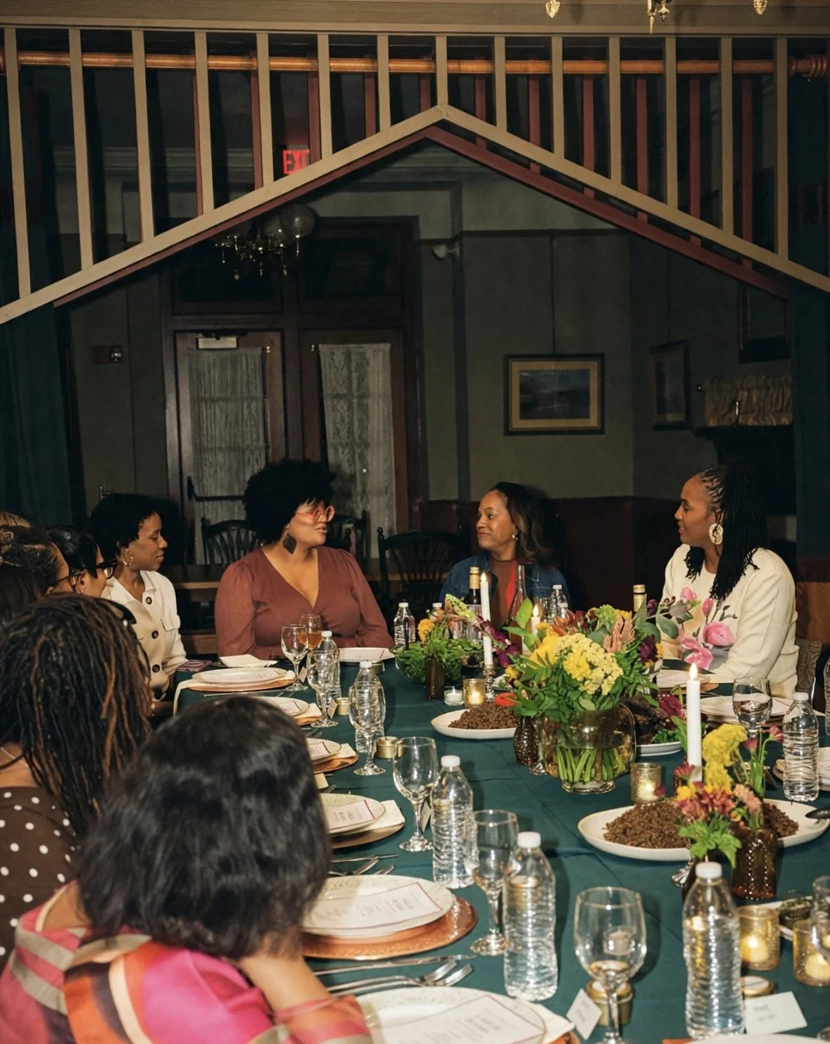 Guests seated around a candlelit dinner table at A Table for the Senses, with fresh flowers, warm lighting, and an intimate table setting in a historic dining room.