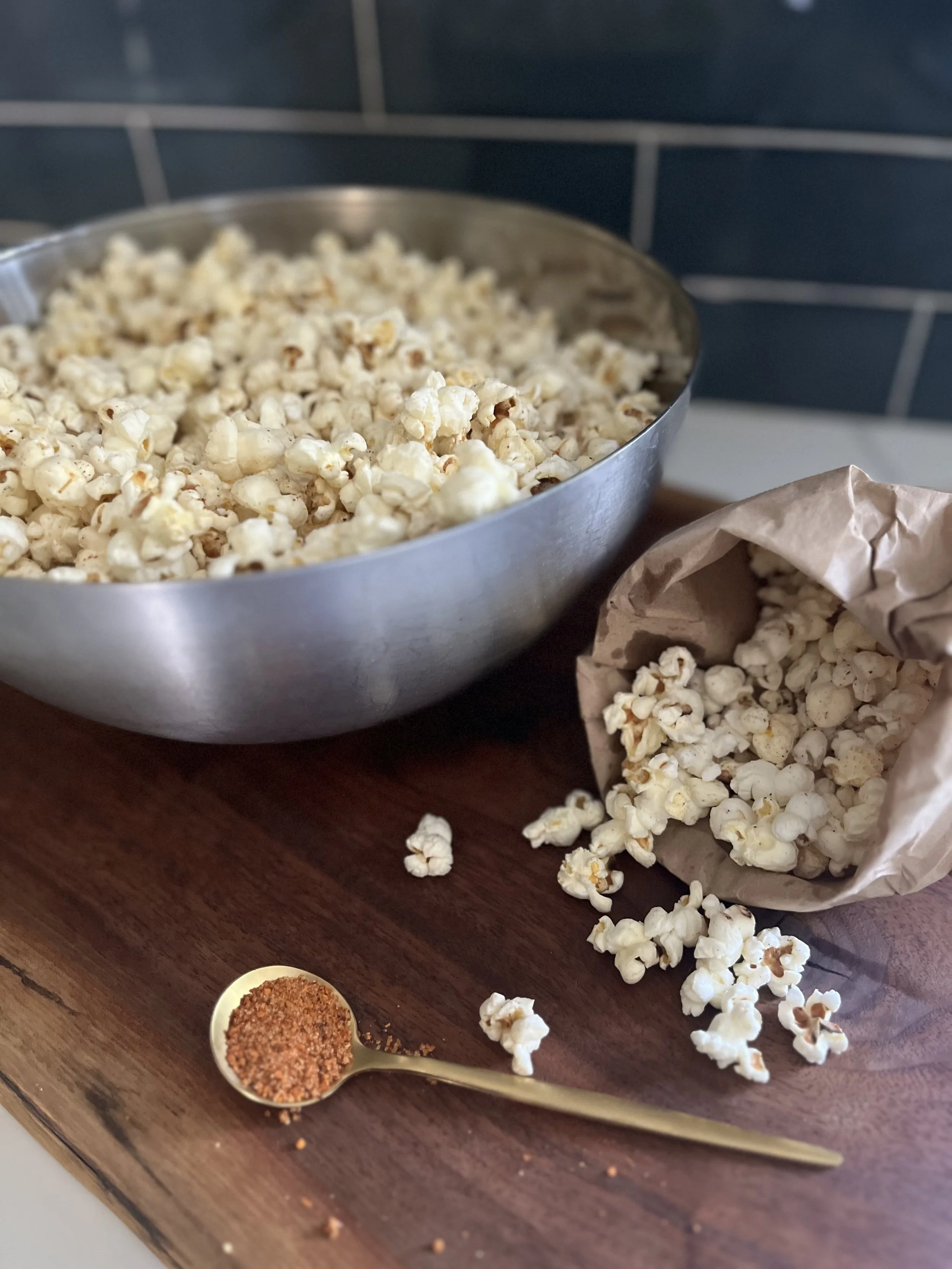 A bowl of homemade popcorn with Tajín seasoning on a wooden cutting board, styled for family movie night.