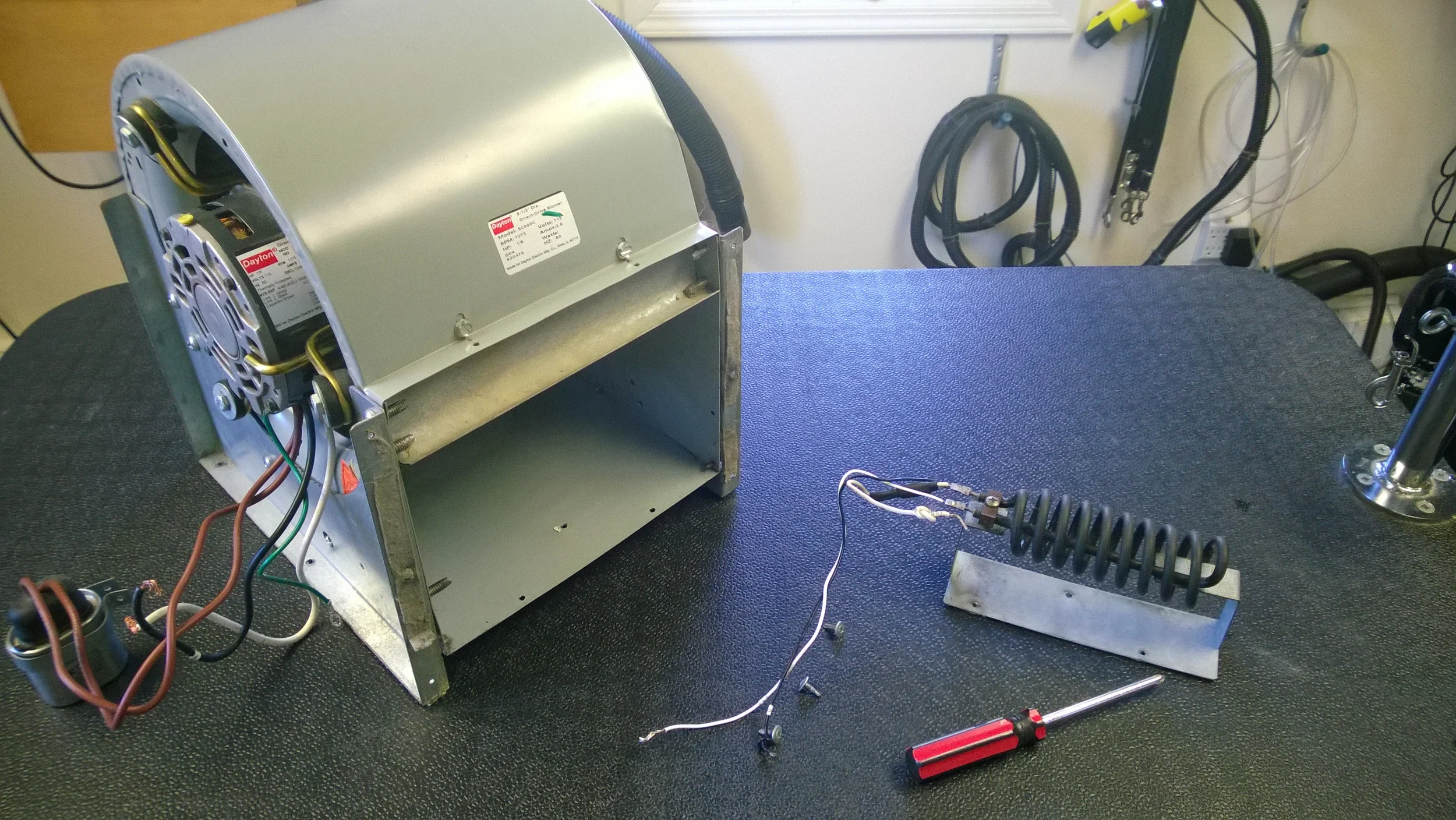  Here you can see the blower motor (left) removed from our kennel dryer. You can also see the heating element completely removed (right). The element bolts to the inside of the blower motor via the three holes on the mounting plate. 