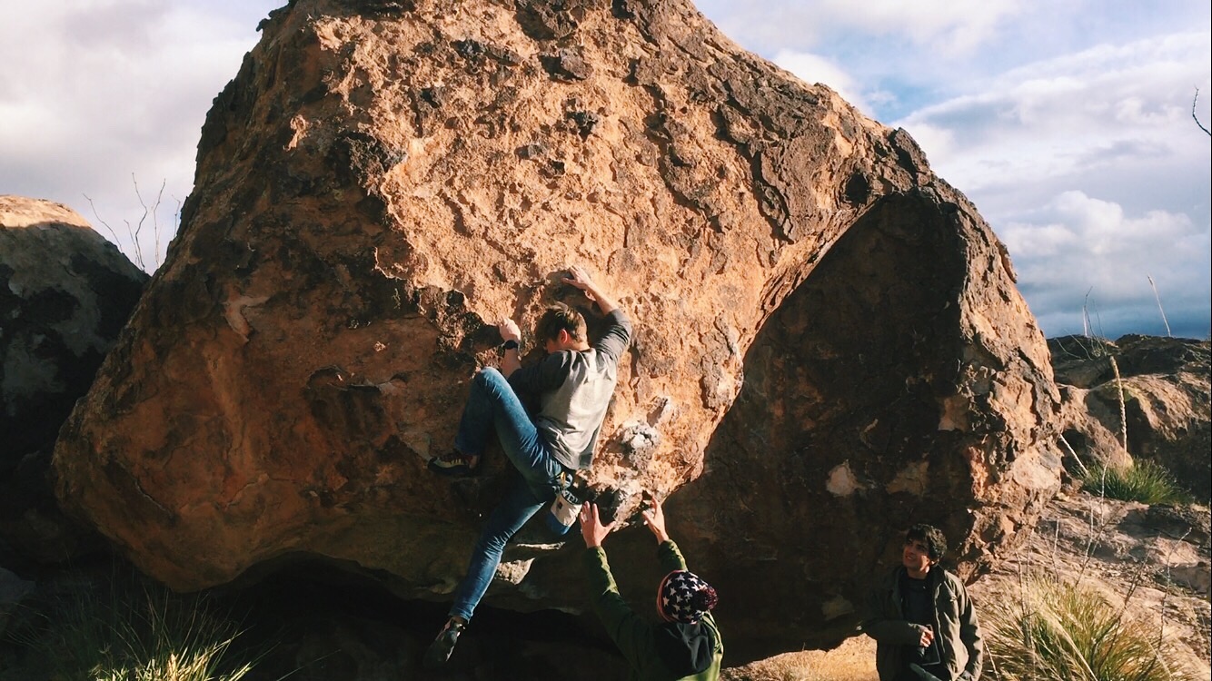 Myself climbing a boulder with two of the people we met Spotting/Giving me Beta.