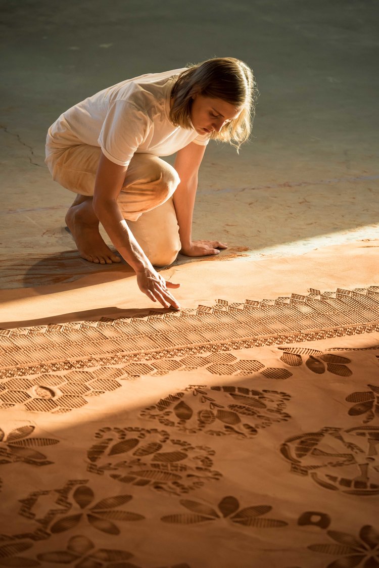 Rena Detrixhe presses designs into a Red Dirt Rug installation. Photo by: Mark Andrus