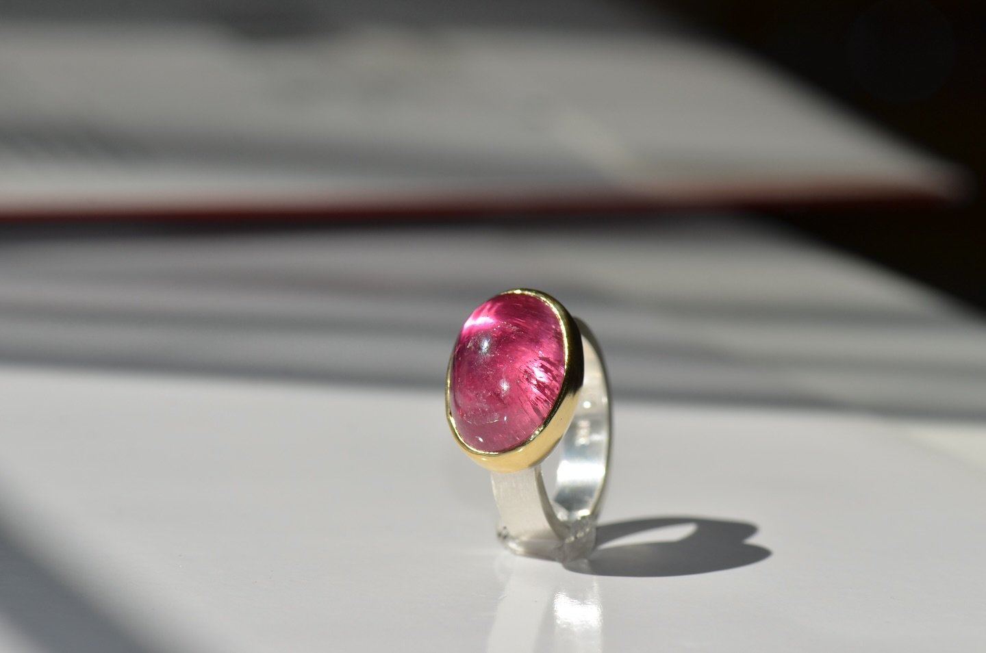 Pink Tourmaline from the popular mine in Pala, California, has the classic &ldquo;bubble gum pink&rdquo; that this particular mine is world famous for. It catches de light wonderfully.  Framed by an 18k solid gold bezel and sterling silver band.

ONE
