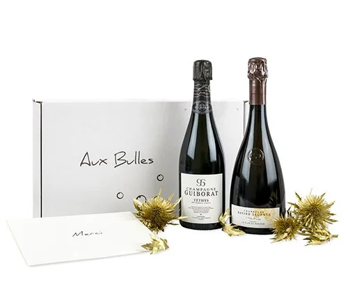 Zwei Flaschen Champagner vor einer Aux Bulles Champagnerabo Box mit vergoldeten Disteln dekoriert
