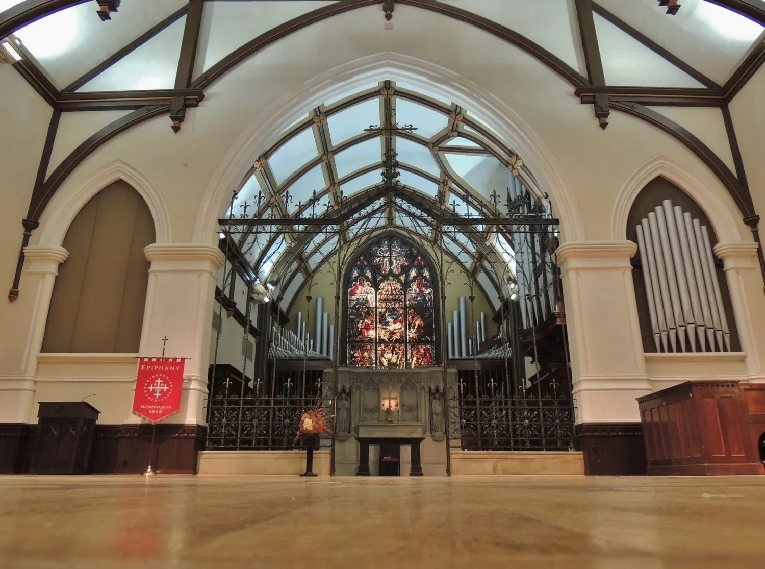Interior of the Church of the Epiphany sanctuary in Washington, DC, with a vaulted ceiling, stained glass, and pipe organ.