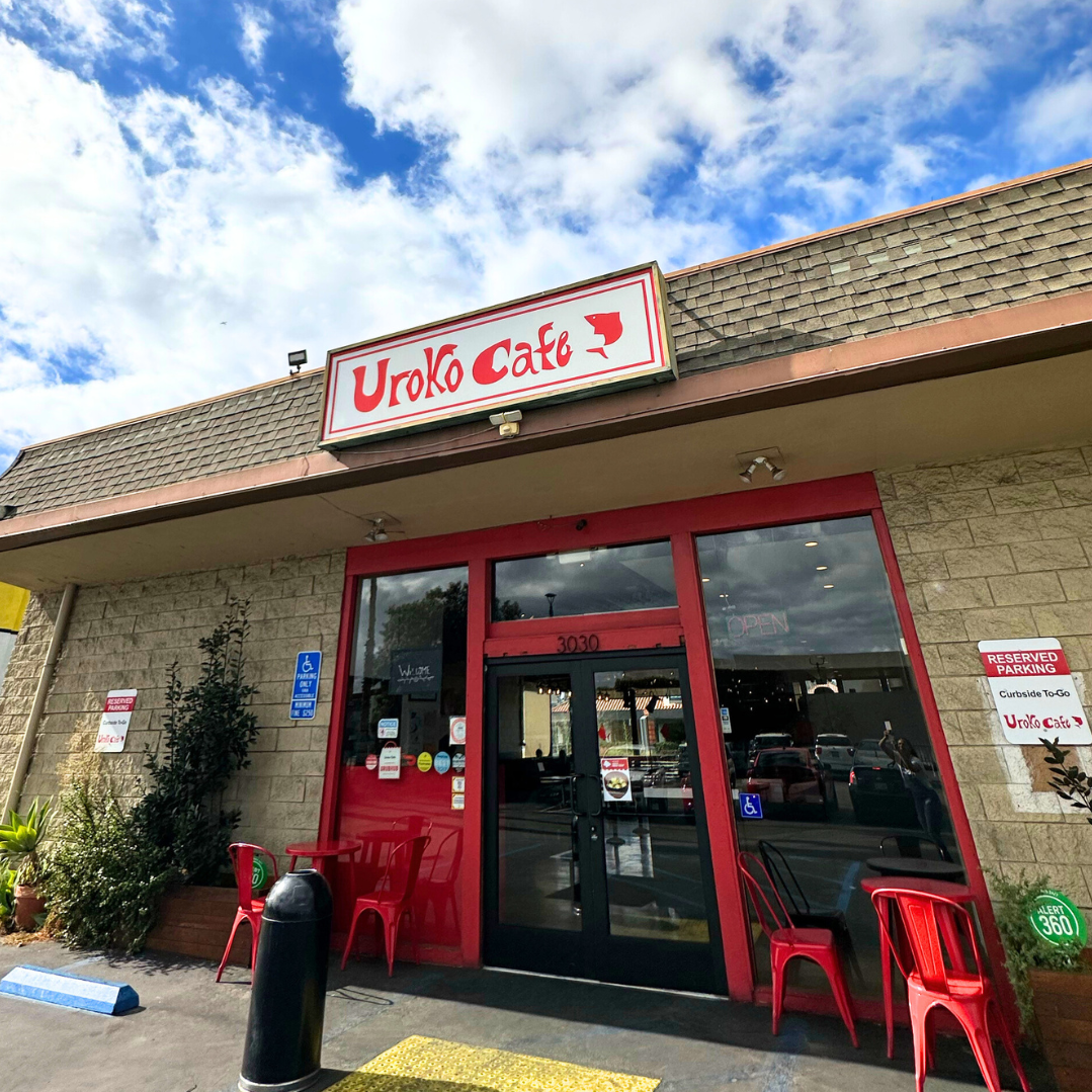 Exterior of Uroko Poke restaurant with red signage and entrance under a blue sky