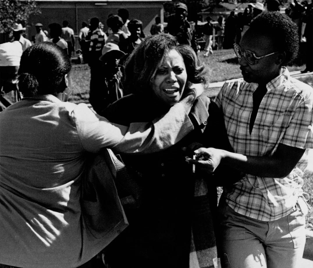 Two neighbors offer their support to a grief stricken woman. Photograph courtesy of the Atlanta Journal Constitution. 