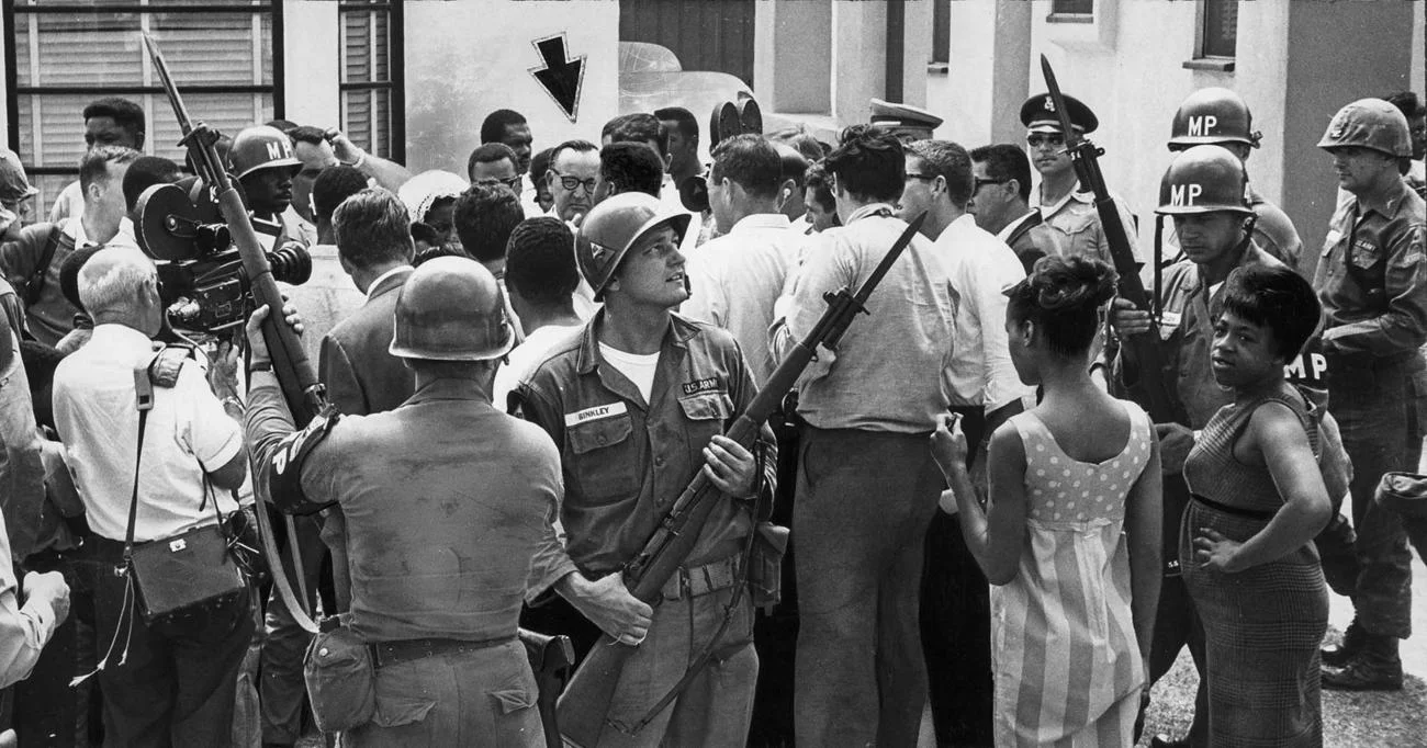 Local residents and journalists converge on California Gov.Pat Brown, under arrow, as he arrives at Jacob Riis High School to have lunch with high-ranking National Guard officers. (Bill Murphy / Los Angeles Times) 1965