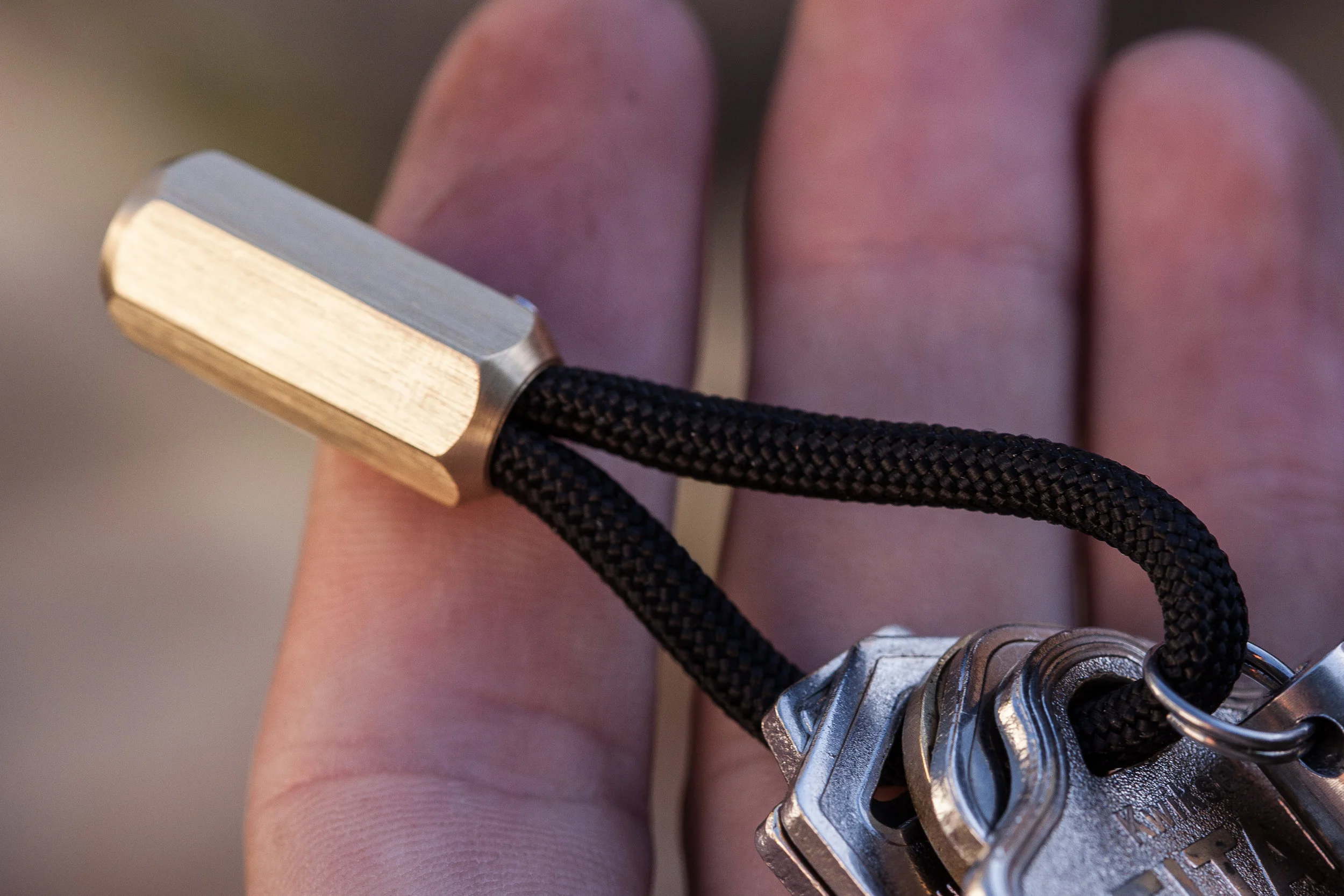 Close up detail of the brass hex Cord Lock with black 550 paracord and keys.