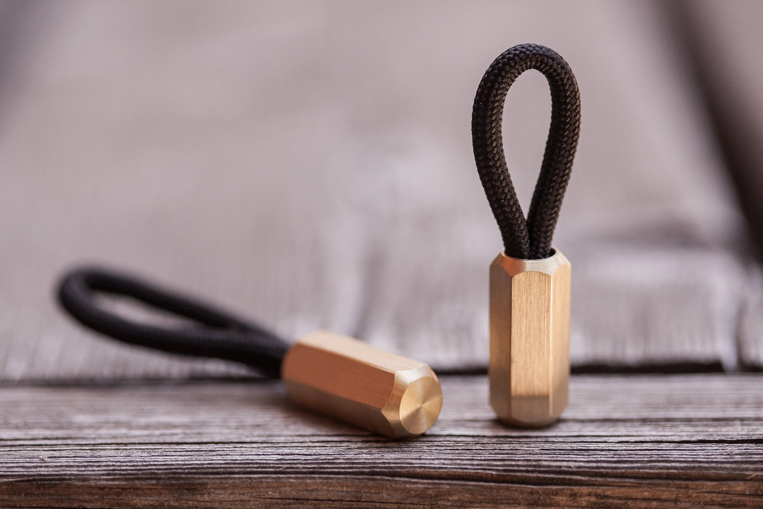 The brass hex version of the Cord Locks shown laying down and standing up with black 550 paracord.