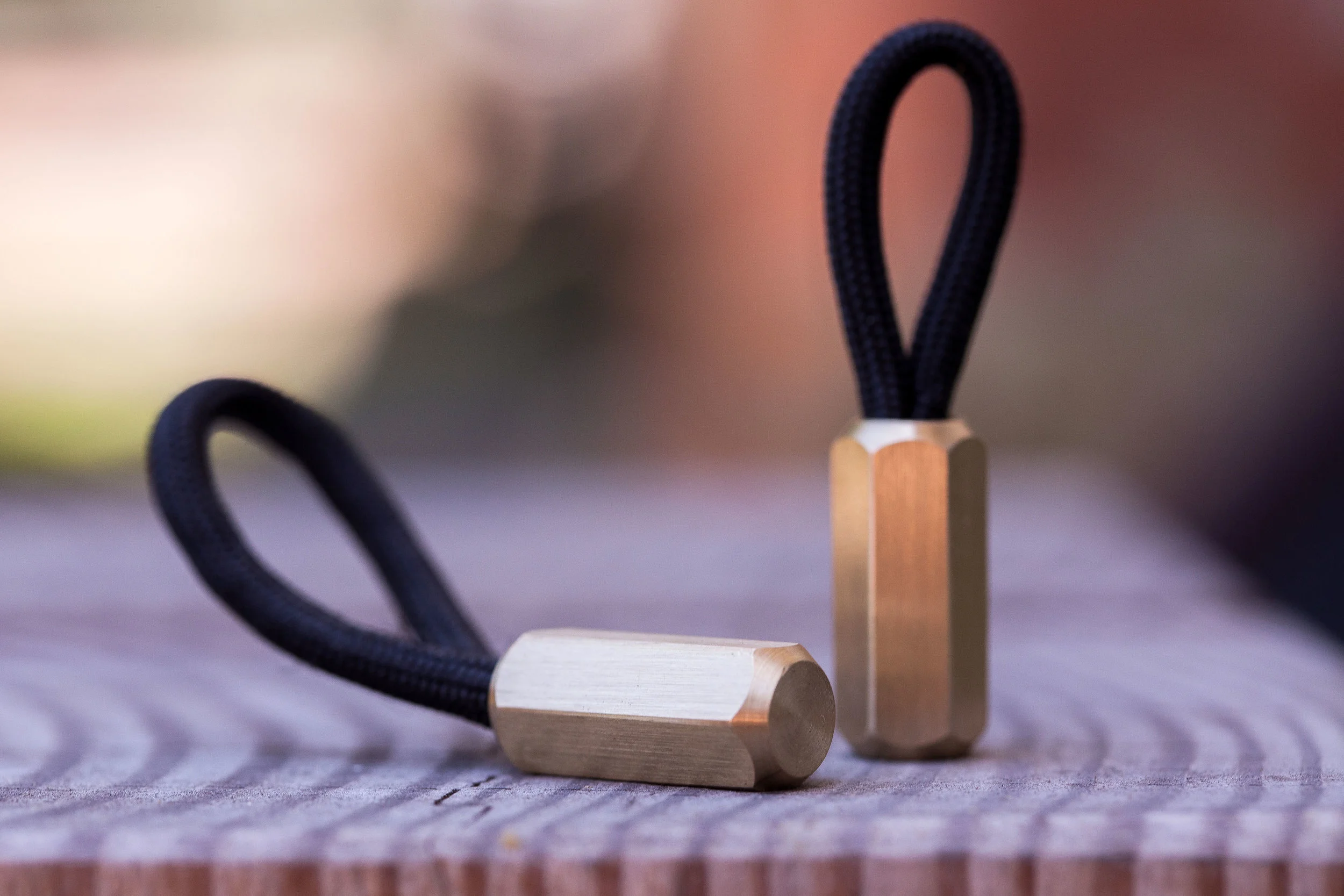 The brass hex version of the Cord Locks shown from two sides with black 550 paracord.