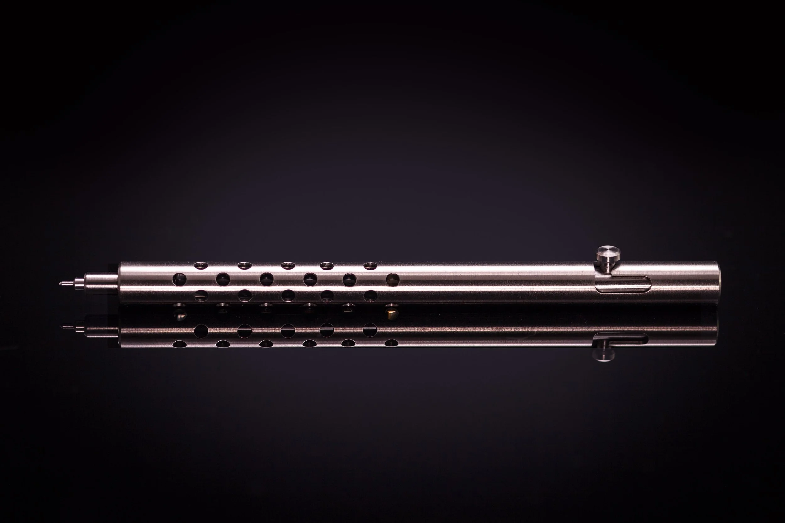 Silencer version of the Injector titanium bolt action pen laying on table.